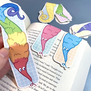 May include: A set of rainbow worm bookmarks. The bookmarks are made of paper and have a glossy finish. The worms are all different colors and have big eyes. The bookmarks are perfect for adding a touch of fun to your reading.