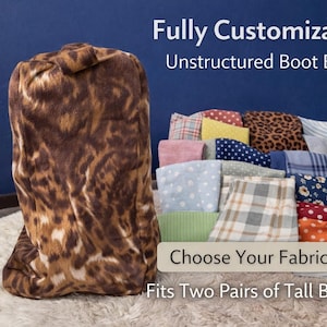 May include: A brown and tan unstructured boot bag with a leopard print pattern. The bag is next to a display of various fabric swatches. Text on the image reads "Fully Customizable Unstructured Boot Bag" and "Choose Your Fabric. Fits Two Pairs of Tall Boots."