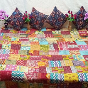 May include: A colorful patchwork quilt with a variety of patterns and colors, including red, yellow, blue, and green. The quilt is made of recycled saris and is perfect for adding a touch of bohemian style to any room.