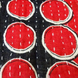 Puede incluir: Primer plano de una tela roja y negra con un patr&oacute;n repetitivo de c&iacute;rculos cosidos en blanco. Los c&iacute;rculos est&aacute;n rellenos de un color rojo s&oacute;lido y est&aacute;n delineados en blanco.