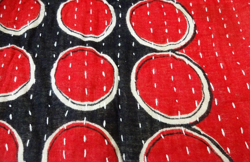 Puede incluir: Primer plano de una tela roja y negra con un patr&oacute;n repetitivo de c&iacute;rculos cosidos en blanco. Los c&iacute;rculos est&aacute;n rellenos de un color rojo s&oacute;lido y est&aacute;n delineados en blanco.