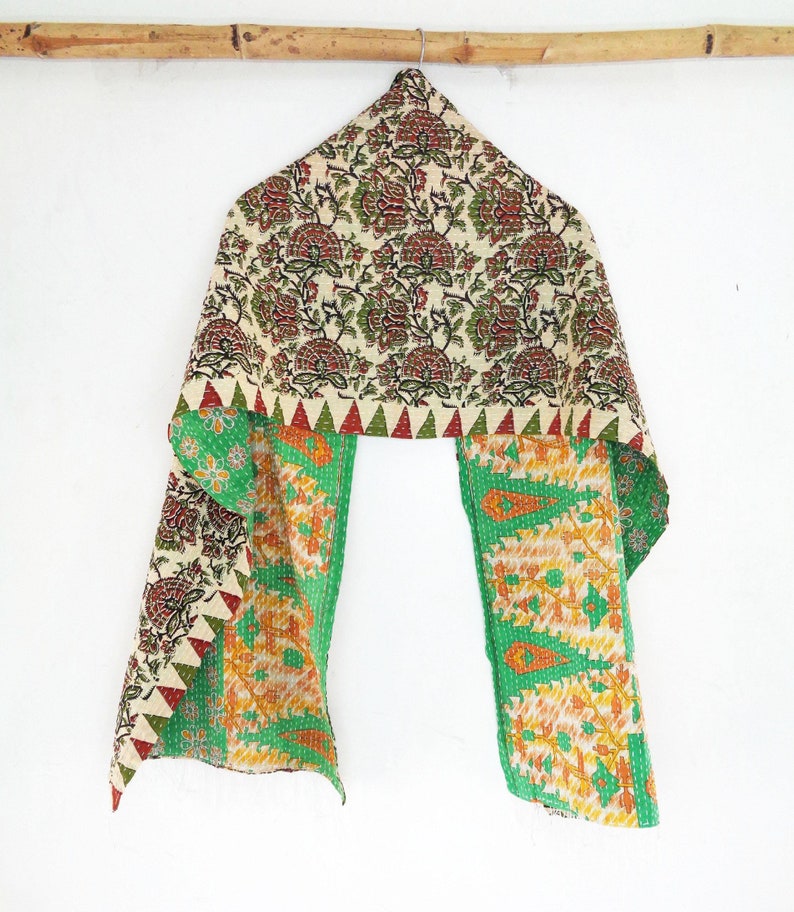 May include: A green and cream kantha scarf with a floral pattern. The scarf is made of recycled saris and is hand-stitched.