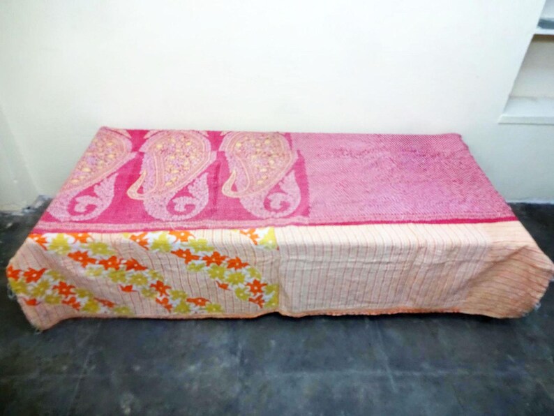 Puede incluir: Una colcha kantha rosa y blanca con un patr&oacute;n de paisley y dise&ntilde;o floral. La colcha est&aacute; hecha de saris reciclados y es perfecta para agregar un toque de estilo bohemio a tu hogar.