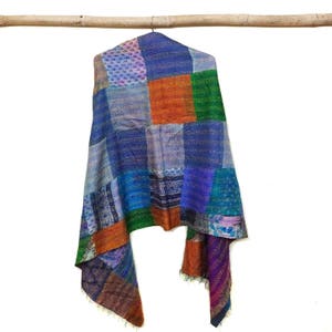 Puede incluir: Una bufanda de seda patchwork con un esquema de color azul, verde, naranja y morado. La bufanda está hecha de muchas piezas diferentes de tela cosidas juntas.