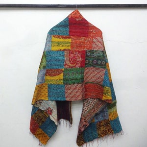 Puede incluir: Bufanda de retazos con una variedad de colores, incluyendo rojo, azul, verde y amarillo. La bufanda está hecha de diferentes cuadrados de tela cosidos juntos. La bufanda cuelga contra una pared blanca.