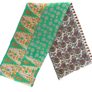 May include: A green, orange, and white kantha quilt with a floral pattern. The quilt is folded in half and has a red and green border.