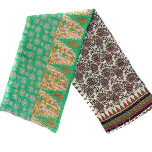 May include: A green and white kantha quilt with floral and paisley patterns. The quilt is folded in half and has a fringed edge.