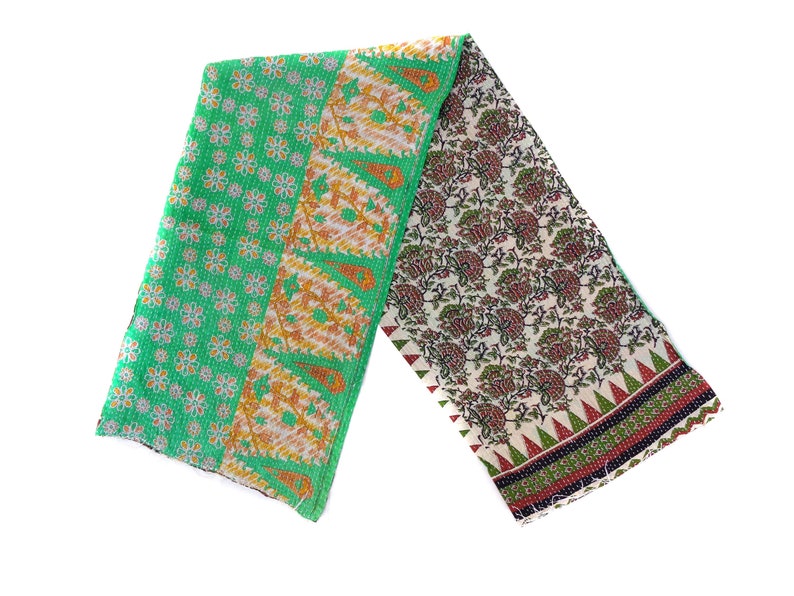 May include: A green and white kantha quilt with floral and paisley patterns. The quilt is folded in half and has a fringed edge.
