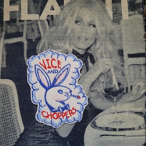 May include: Embroidered patch featuring a cartoon bunny smoking a cigarette, with the text "VICE AND CHOPPERS" in red and blue. The patch is on a denim background with a black and white image of a woman.