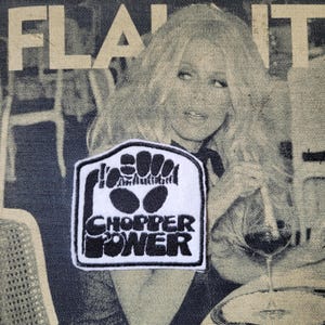 Puede incluir: Un parche blanco y negro con las palabras "Chopper Power" y otro texto. El parche está sobre un fondo de mezclilla con una imagen en blanco y negro de una mujer y la palabra "FLAUNT".