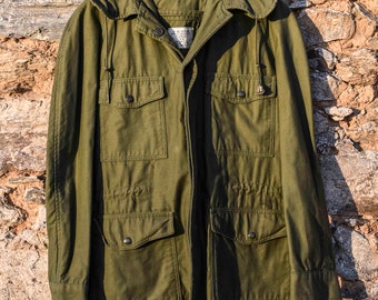 May include: A green hooded jacket with multiple pockets and a drawstring hood. The jacket has a button closure and a label that reads "Made in USA".