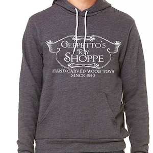 May include: A dark gray hooded sweatshirt with a white graphic design that reads "Geppetto's Toy Shoppe" and "Hand Carved Wood Toys Since 1940".