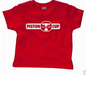 Puede incluir: Camiseta roja con un logotipo blanco de Piston Cup Racing Series. El logotipo presenta un trofeo con alas.