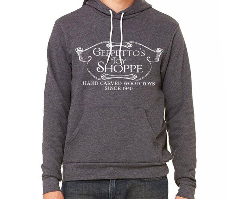 May include: A dark gray hooded sweatshirt with a white graphic design that reads "Geppetto's Toy Shoppe" and "Hand Carved Wood Toys Since 1940".