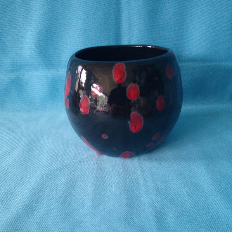 May include: A black ceramic bowl with red polka dots. The bowl is round and has a smooth, glossy finish.