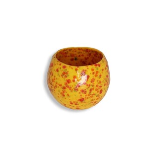 May include: A yellow ceramic bowl with a speckled red and orange design.