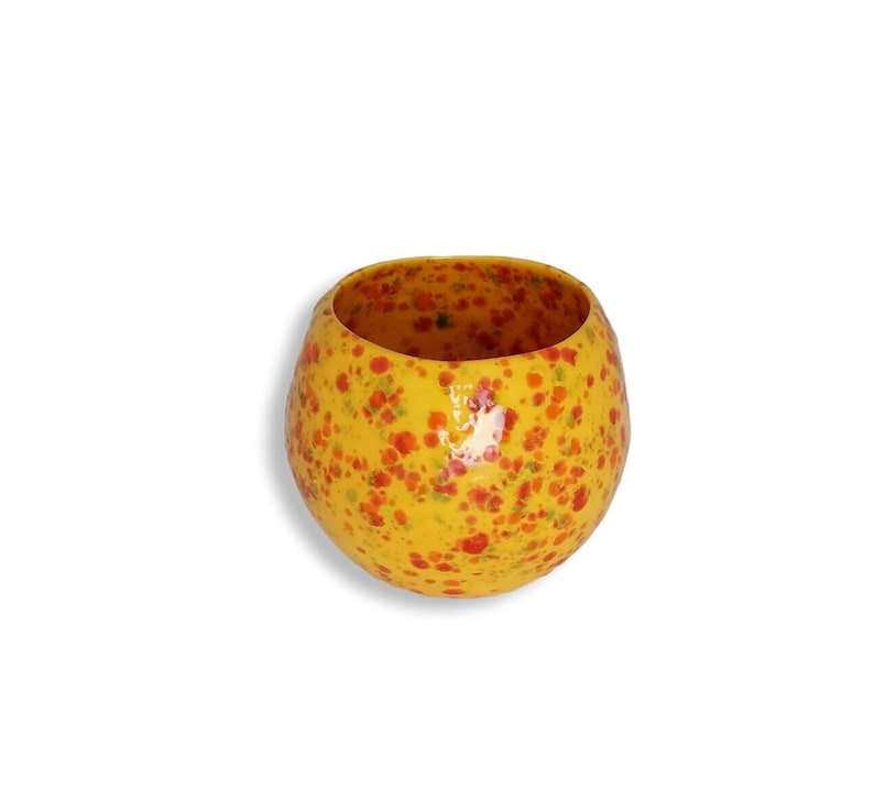 May include: A yellow ceramic bowl with a speckled red and orange design.