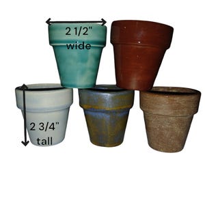 May include: Five small ceramic flower pots in various colors. The teal pot is 2 1/2 inches wide. The off-white pot is 2 3/4 inches tall. Other colors include brown, blue, and tan. These pots are ideal for small plants.