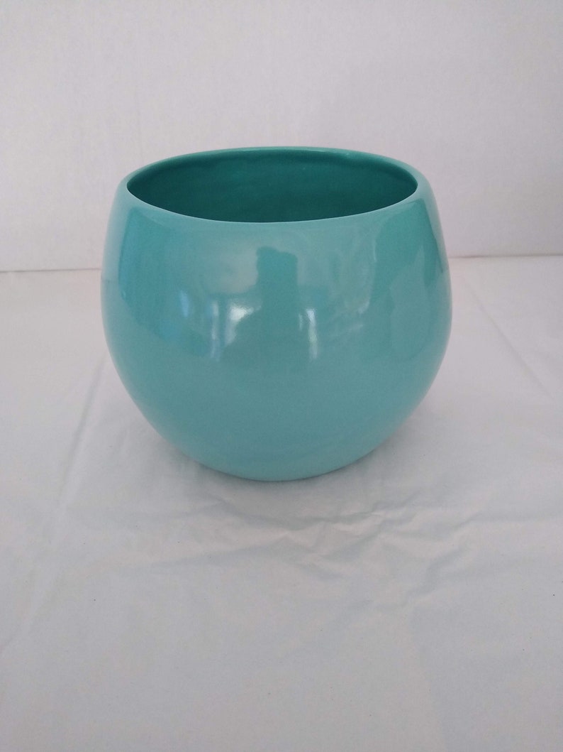 May include: A light blue ceramic planter with a rounded shape.
