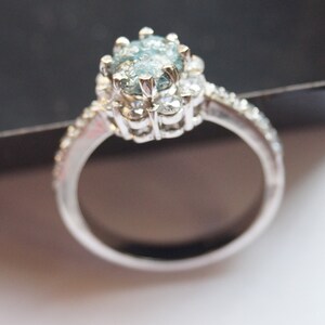 May include: A silver ring with a large, oval-shaped blue gemstone surrounded by smaller diamonds.