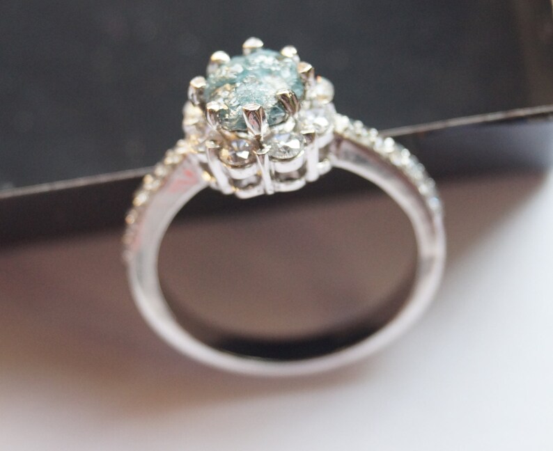 May include: A silver ring with a large, oval-shaped blue gemstone surrounded by smaller diamonds.