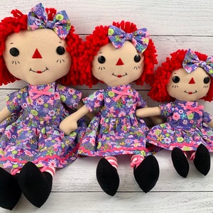 Raggedy Ann style doll is dressed in a removable floral light purple dress with matching hair bow. 
She has light tan skin tone with red hair. Recommended for ages 3 and up.
Doll Sizes:
Small 13 inches
Medium 16 inches
Large 20 inches