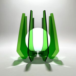 Op de afbeelding: Een moderne groene lamp met een witte, bolvormige lichtbron. De lamp heeft een reeks hoekige, transparante groene panelen die het licht omcirkelen. Het ontwerp werpt interessante schaduwen en creëert een eigentijdse esthetiek.