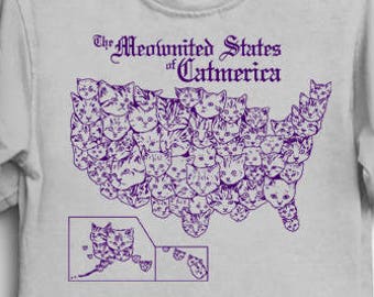 May include: A gray t-shirt with a purple print of a cat-shaped outline of the United States. The text "The Meownited States of Catmerica" is printed above the map.