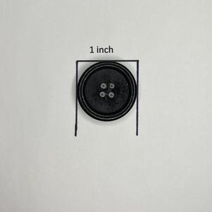 May include: A black button with four holes, approximately 1 inch in diameter, is shown within a drawn square. The button has a ridged outer edge. The text "1 inch" is above the square.
