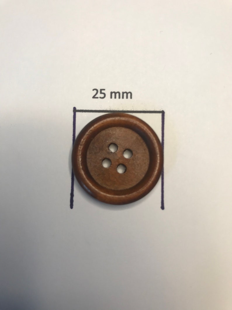 May include: A round, brown wooden button with four holes. The button is 25 mm in diameter, as indicated by the text and measurement lines. The button is set against a white background.