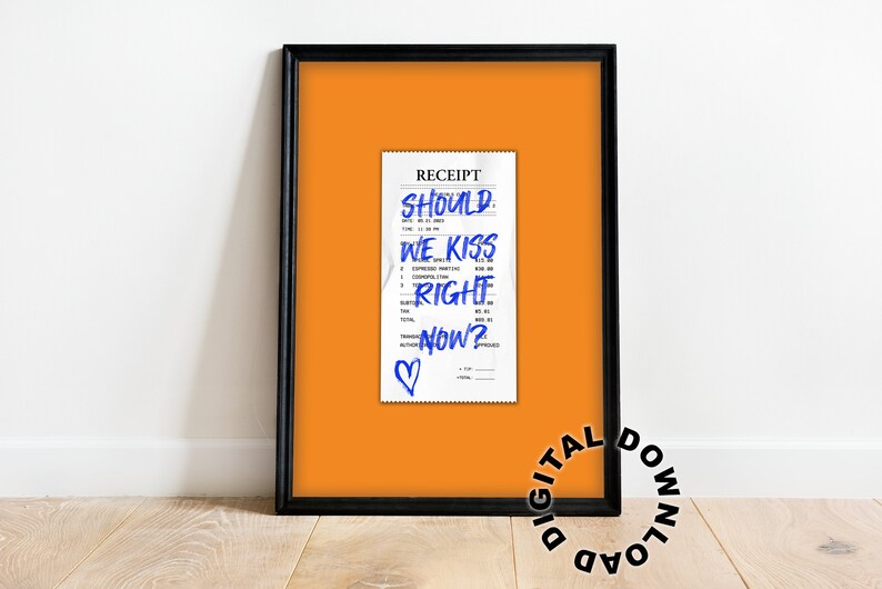 Puede incluir: Una impresi&oacute;n enmarcada de un recibo con las palabras "Should we kiss right now?" escritas en tinta azul. Un coraz&oacute;n est&aacute; dibujado en la parte inferior del recibo. El fondo es naranja.