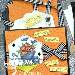 May include: A Halloween card with an orange background and a black and white checkered ribbon. The card features a black and white illustration of crows pushing a wheelbarrow full of pumpkins. The card also includes the text "May your Halloween be full of smiles!" and "Created by Elizabeth Terrell".