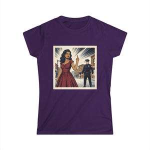 May include: A dark purple short-sleeved t-shirt featuring a square graphic print of a comic book style scene. The illustration depicts a person in a red polka dot dress gesturing with a middle finger toward a police officer on a city street.