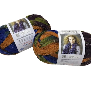 May include: Two skeins of Red Heart Sashay yarn in the color Rumba, featuring a multi-colored ribbon-like texture with shades of blue, green, and copper. Each label displays a photo of a finished scarf, a 5.5 mm or US 9 needle size, and a QR code.