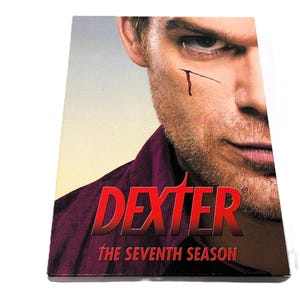 May include: A DVD cover for the seventh season of the television show Dexter. The cover features a close-up of Michael C. Hall as Dexter Morgan, with the show's title in red letters and the season number in white letters.