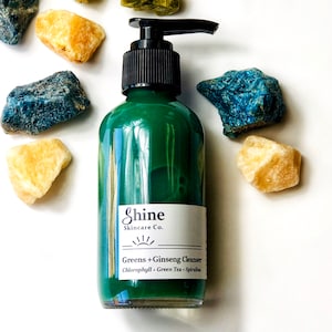 Puede incluir: Una botella de vidrio verde con un dispensador de bomba que contiene un l&iacute;quido verde. La botella est&aacute; etiquetada con "Shine Skincare Co. Greens + Ginseng Cleanser Chlorophyll - Green Tea - Spirulina"