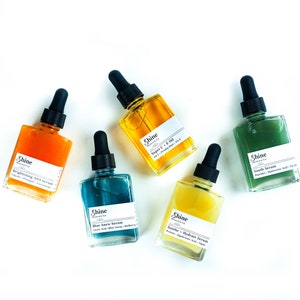 May include: Five glass bottles with dropper tops containing different serums. The bottles are labeled with the brand name "Shine Skincare Co." and the names of the serums: "Brightening AHA Serum", "Super C + E Oil", "Blue Algae Serum", "Soothe + Hydrate Serum", and "Youth Serum".