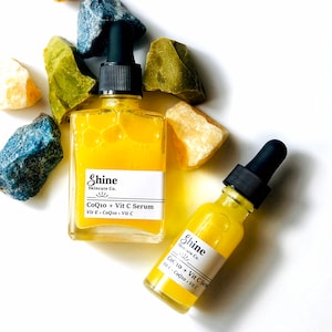 May include: Two glass bottles of yellow serum with dropper tops. The bottles are labeled "Shine Skincare Co. CoQ10 + Vit C Serum Vit E - CoQ10 - Vit C".