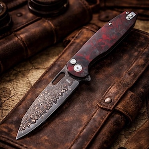 May include: A folding knife with a patterned blade and a red and black handle rests on a brown leather surface. The blade has a unique, wavy design. The handle features two silver-colored screws and a pocket clip.