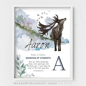 May include: A watercolor illustration of a deer with large antlers standing on a mountain with a blue sky and birds flying above. The name "Aaron" is written in cursive below the deer. The text "Origin is Hebrew. Mountain of Strength. And all these blessings shall come upon you and overtake you, if you obey the voice of the Lord your God. Deuteronomy 28:2" is written below the name. The letter "A" is in a large font in the bottom right corner.