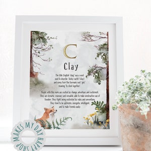 May include: A framed art print with the name "Clay" in a decorative font. The print features watercolor illustrations of trees, a fox, and flowers. The text describes the origin and meaning of the name.
