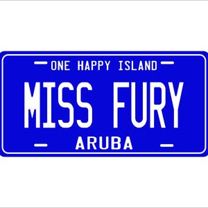 May include: Blue license plate with white text that reads "One Happy Island" at the top, "Miss Fury" in the center, and "Aruba" at the bottom.