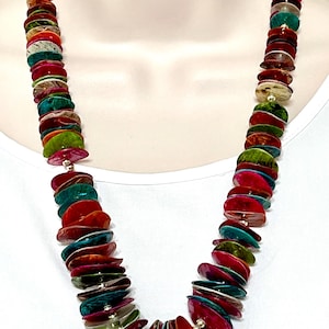May include: A colorful necklace featuring iridescent, flat, round beads in shades of red, green, teal, and gold. The beads are strung together, creating a layered effect. The necklace is displayed on a white background.