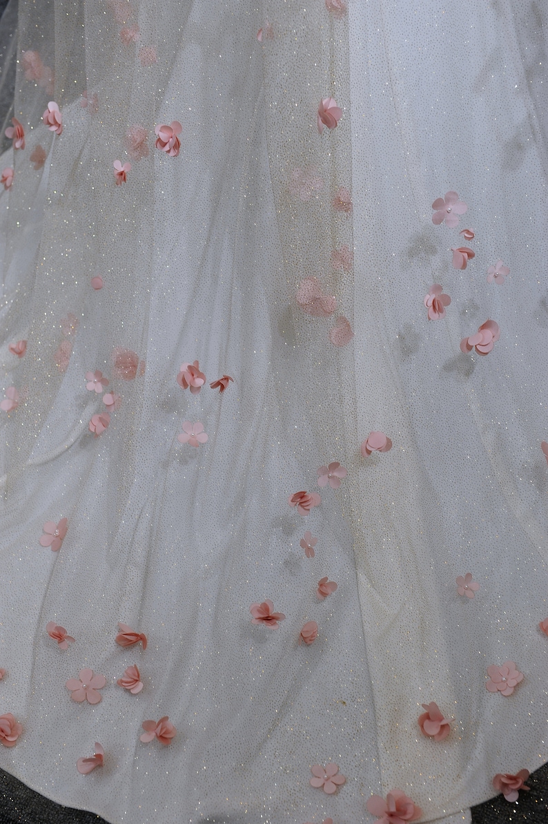 K&ouml;nnte beinhalten: Ein wei&szlig;er T&uuml;llstoff mit rosa Blumenverzierungen. Der Stoff hat einen dezenten Glanz.