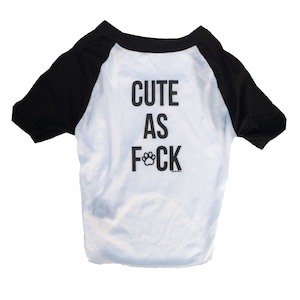 May include: White and black dog t-shirt with the text "Cute as F*ck" with a paw print replacing the "C".