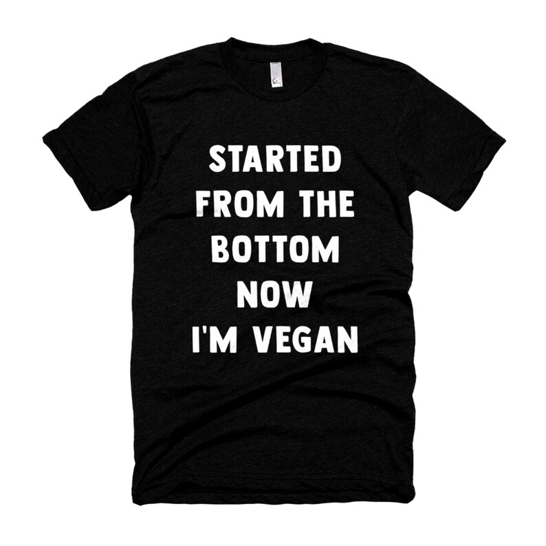 May include: Black t-shirt with white text that reads "Started from the bottom now I'm vegan."