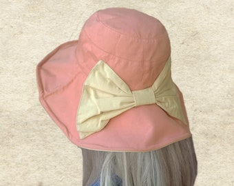 May include: A pink sun hat with a large, cream-colored bow on the back.