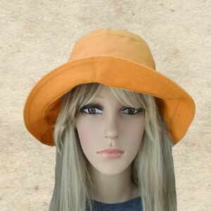 May include: A bright orange sun hat with a wide brim. The hat is made of a soft, lightweight fabric and has a simple, classic design.