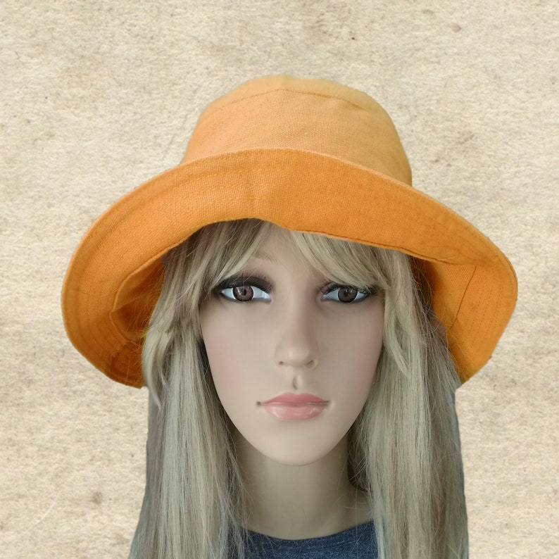 May include: A bright orange sun hat with a wide brim. The hat is made of a soft, lightweight fabric and has a simple, classic design.