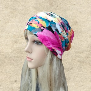 May include: A colorful floral patterned beanie hat with pink, blue, yellow, and white accents. The hat is made of a soft, stretchy fabric and is perfect for casual wear.